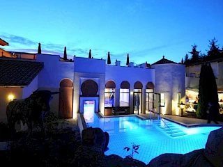 Blick auf die Poollandschaft im Außenbereich des Sieben Welten Hotel & Spa Resort bei Nacht