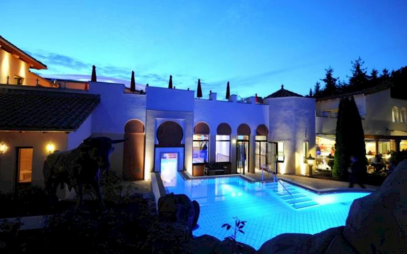 Blick auf die Poollandschaft im Außenbereich des Sieben Welten Hotel & Spa Resort bei Nacht