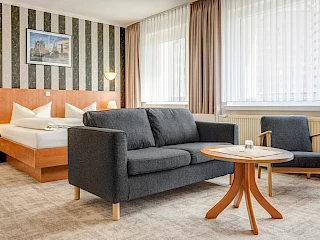 Einblick in das Hotelzimmer des Hotel Wilna in Erfurt mit Doppelbett und Sitzgelegenheit