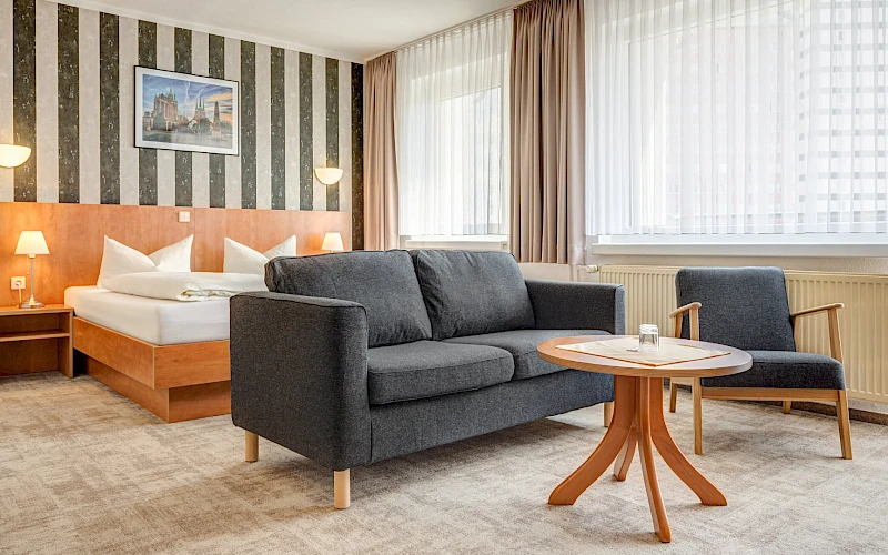 Einblick in das Hotelzimmer des Hotel Wilna in Erfurt mit Doppelbett und Sitzgelegenheit